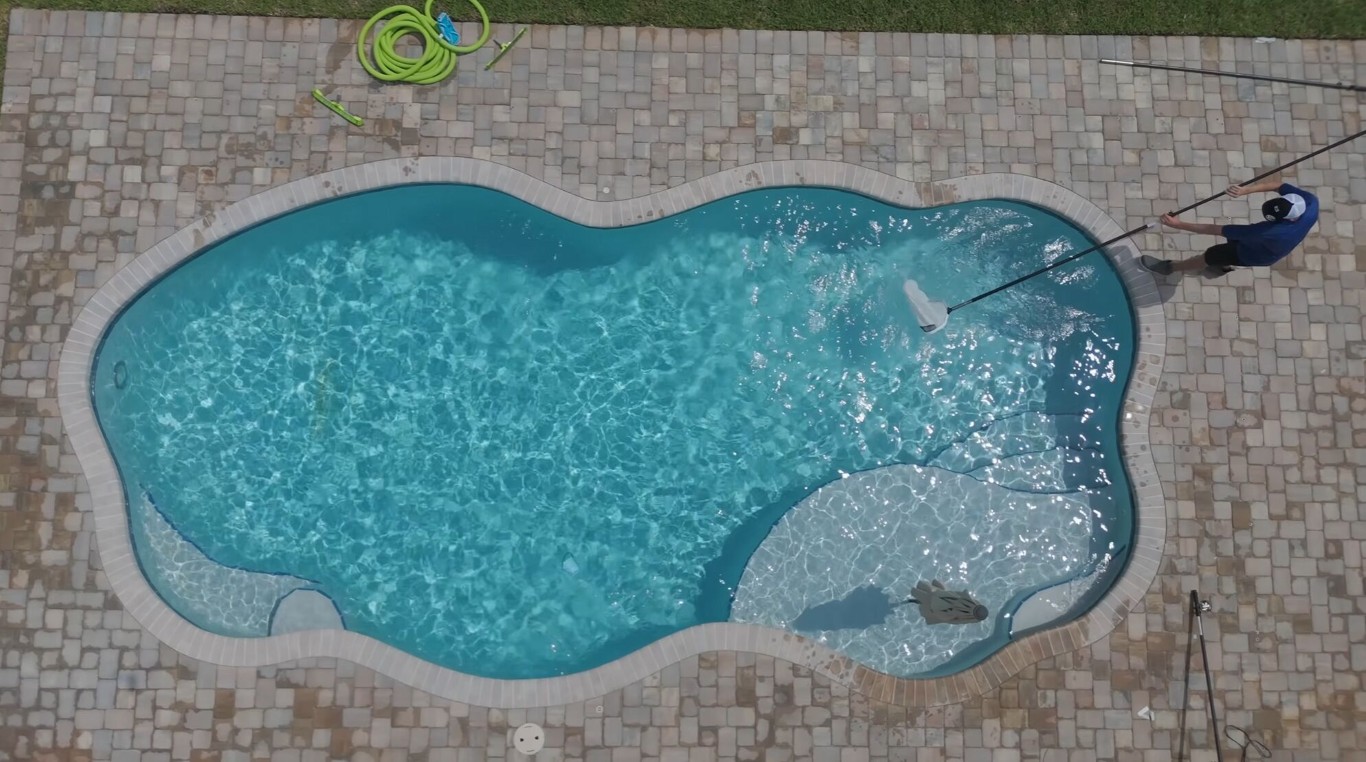 Aerial view of professional pool technician servicing a freeform pool in Placentia, CA